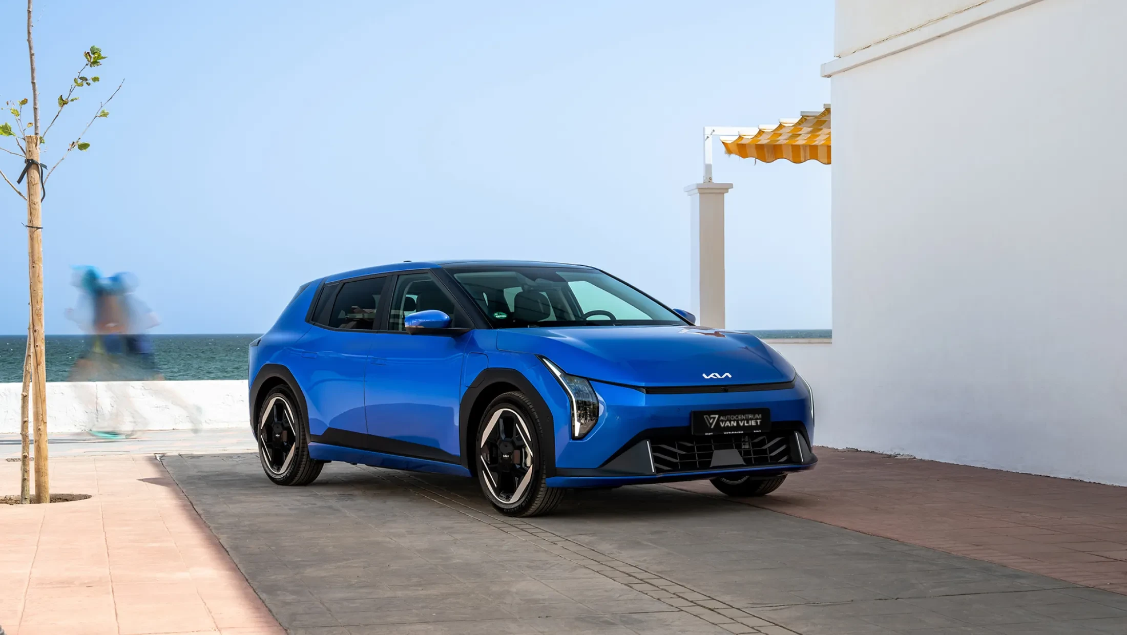 Kia EV4 in het blauw, naast de zee