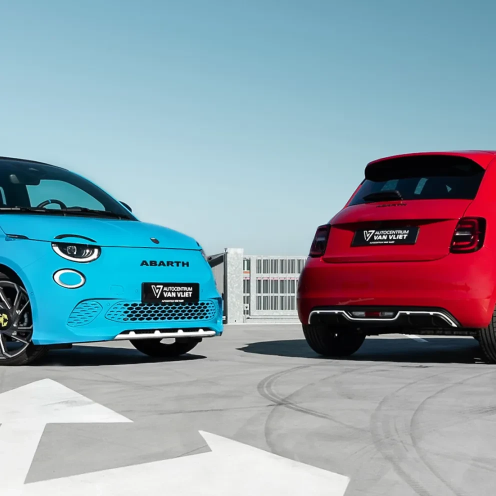 Twee Abarth 500's, één in felblauw en één in rood, staan sportief gepositioneerd op een leeg parkeerdek 