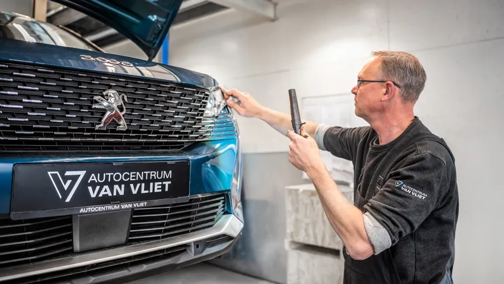 Een monteur controleert de koplamp van een auto als onderdeel van een APK-inspectie.