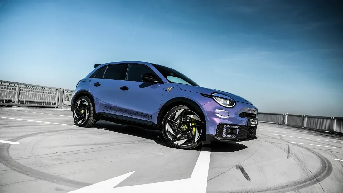 Een nieuwe Abarth 600e in Hypnotic Purple staat geparkeerd op een parkeerplaats. 